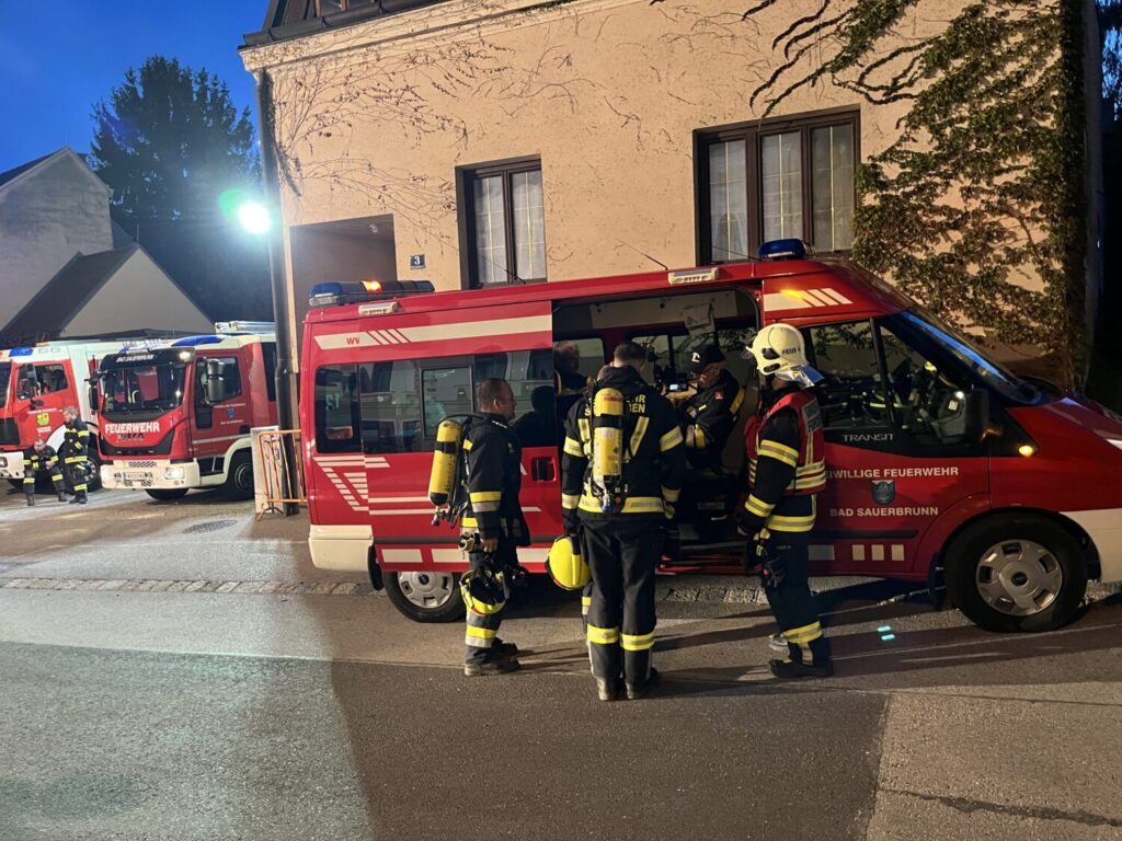 Feuerwehrleute in Uniformen und mit Ausrüstung stehen vor einem Feuerwehrauto in Bad Sauerbrunn