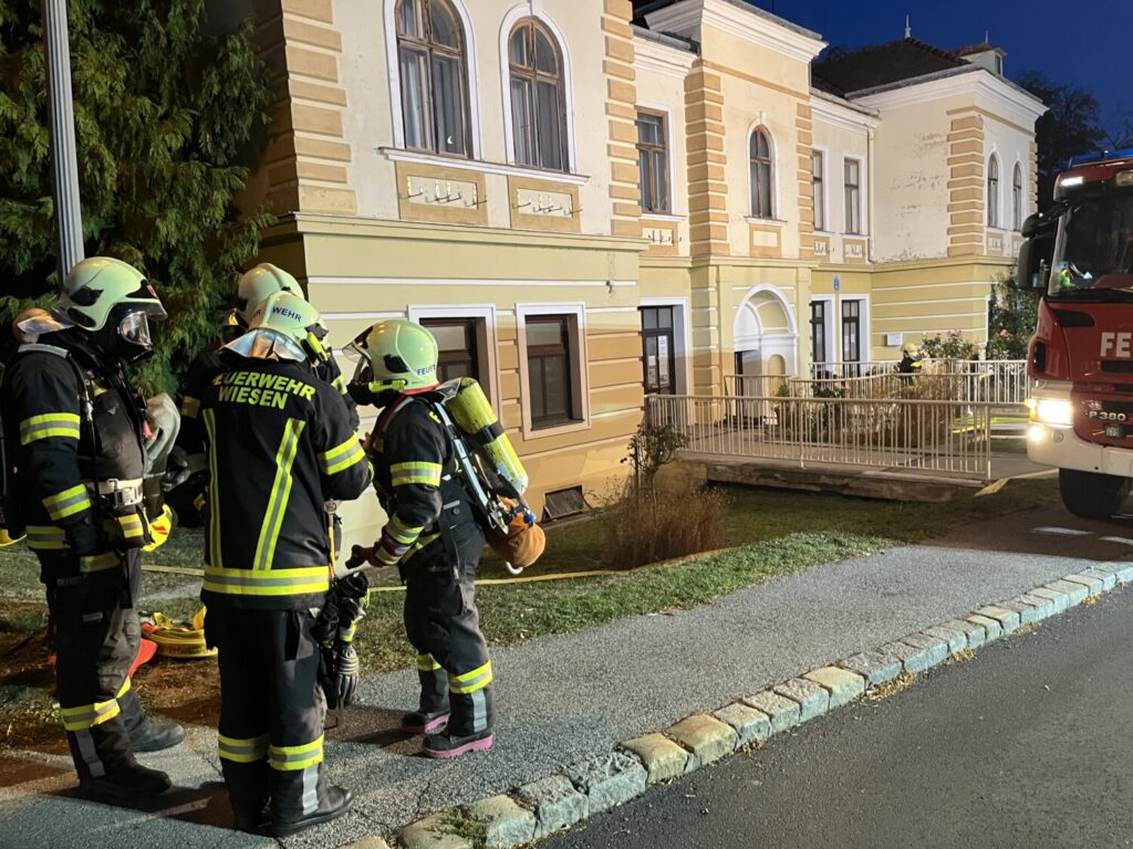 Feuerwehr Wiesen im Einsatz vor einem gelben Gebäude mit einem roten Feuerwehrauto